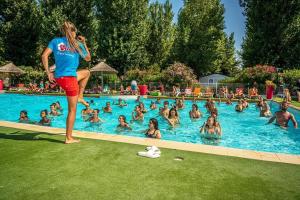 a woman standing in a swimming pool with a crowd of people at ZEcamping 4 étoiles 500m plage piscine couverte animaux acceptés club enfant in Sérignan