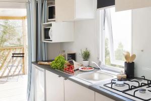 a kitchen with white cabinets and a sink and a window at ZEcamping 4 étoiles 500m plage piscine couverte animaux acceptés club enfant in Sérignan