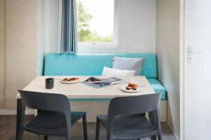 a dining table with two chairs and a blue couch at ZEcamping 4 étoiles 500m plage piscine couverte animaux acceptés club enfant in Sérignan