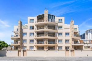 a tall white building with balconies on it at Coral Grove in Strand