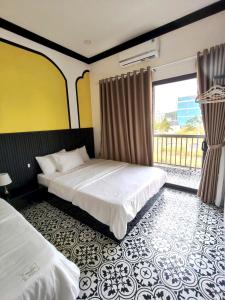 a hotel room with two beds and a balcony at Villa RonRoy Hà Tiên in Hà Tiên