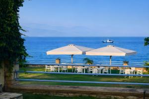 a group of tables and umbrellas next to the ocean at Alexandros Beachfront Apartments near Petalidi with Private Sunbeds & Sea View in Kalamaki Messinia