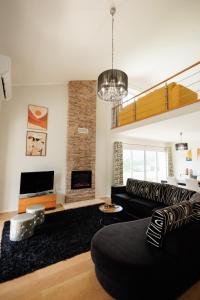 a living room with a black couch and a fireplace at Home In Green Caldera in Furnas