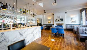 a restaurant with a bar with blue chairs and tables at Ilkley Riverside Hotel in Ilkley