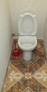 a white toilet in a bathroom with a tile floor at 12 Квартал Шинник in Dnipro