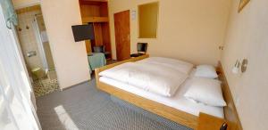 a bedroom with a bed with white sheets and pillows at Hotel Keinath Stuttgart in Stuttgart