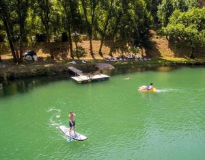 a man riding a paddle board in a lake at ZEcamping 4 étoiles familial animaux acceptés animé équitation in Saint-Rome-de-Tarn +37 photos