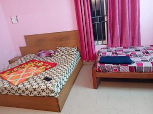a bedroom with two beds and a window with pink curtains at Roamwander doublerooms in Vagamon