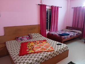 two beds in a room with red curtains at Roamwander doublerooms in Vagamon +2 photos