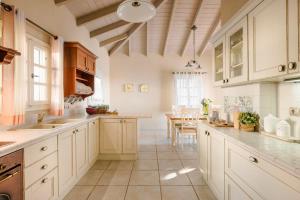 a large kitchen with white cabinets and a table at Nikolas by Vintage Travel in Fiskardo
