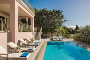 a swimming pool with lounge chairs next to a house at Nikolas by Vintage Travel in Fiskardo