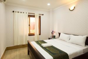 a bedroom with a large white bed with a window at RS Guesthouse in Phnom Penh