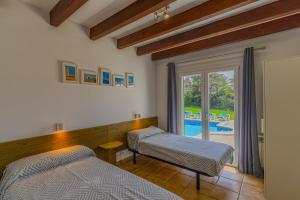 a bedroom with two beds and a window with a pool at Villa Sargantana Negra in Binibeca +19 photos