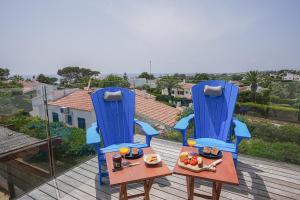 two blue chairs and a table with food on a balcony at Villa Sargantana Negra in Binibeca