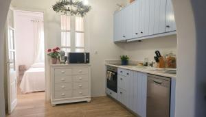 a kitchen with white cabinets and a sink and a microwave at Stunning Sea-View Villa w Access to Shared Pools in Mikonos