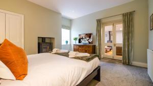 a bedroom with a large white bed with an orange pillow at Summers Nook in Humshaugh +10 photos