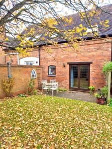 a brick house with a table and chairs in the yard at Charming 2 bed cottage in Milcote Station