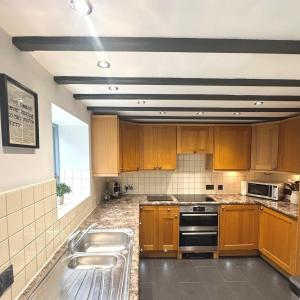 a kitchen with wooden cabinets and stainless steel appliances at Charming 2 bed cottage in Milcote Station +6 photos