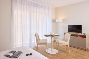 a hotel room with a table and chairs and a television at Quality Aparthotel Voiron in Voiron