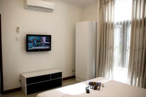 ディリにあるHotel The Ramelauの壁にテレビとベッドが備わる客室です。