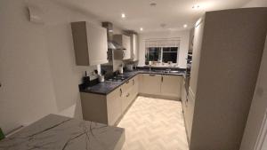 a large kitchen with white cabinets and a window at 3,Lime Tree Ave in Haverfordwest