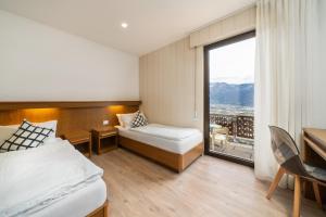 a hotel room with two beds and a large window at Hotel Deva in Riva del Garda