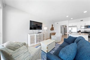 a living room with a blue couch and a kitchen at Sea Glass 404 by Youngs Suncoast in Gulf Shores