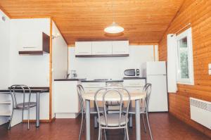 a kitchen with white cabinets and a table and chairs at Chalet 3 étoiles - Piscine - eebbhf in Beynat