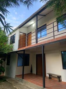 a house with a balcony and a bench in front at hospedaje ecopolis birds in El Queremal