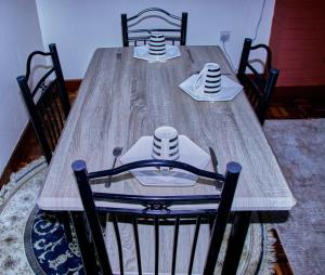 a wooden table with two chairs and two plates and cups at The Haven House in Nairobi +5 photos