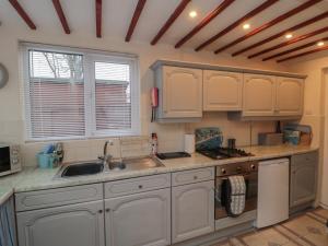 a kitchen with white cabinets and a sink at Seabreeze in Filey +9 photos