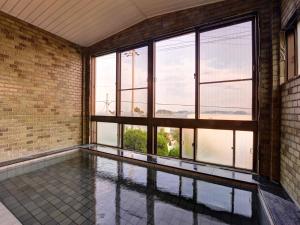 an empty room with a pool and windows at Takumi Kanko Hotel in Minamichita