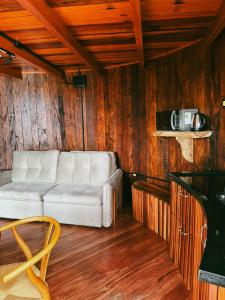 a white couch in a room with wooden walls at Pousada tanoeiro cabana Carvalho in Monte Belo
