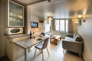 a kitchen and living room with a table and a couch at Le Chat Perché in Escalles