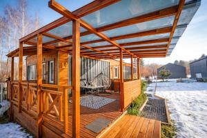a wooden cabin with a covered deck in the snow at Lazy Deer - Camp in Staniszów