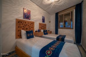 a bedroom with two beds and a chandelier at Dar jawhara in Chefchaouen