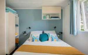 a small bedroom with a bed with blue walls at ZEcamping 4 étoiles animé piscine couverte club enfant mini golf dog friendly in La Faute-sur-Mer
