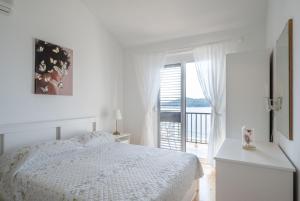 a white bedroom with a bed and a balcony at Apartments Lea in Prizba