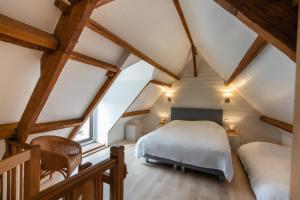 a attic bedroom with a bed and two chairs at Le Chat Perché in Escalles