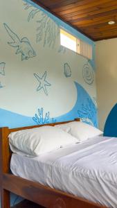 a bedroom with a bed with a painting on the wall at Drop House Hostel - Surf & Skate - Itamambuca in Ubatuba