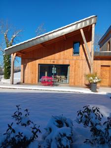 a wooden building with a red table in front of it at Gîte Jurassien in Clairvaux-les-Lacs