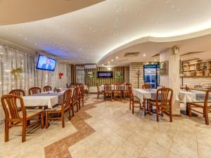 ein Restaurant mit Tischen und Stühlen und einem Flachbildfernseher in der Unterkunft Hotel Elit in Dewin