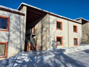 a building with snow on the ground in front of it at APT C-3 v areálu DOKY LIPNO - bezbariérový in Lipno nad Vltavou