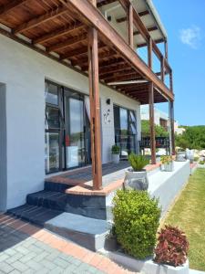 a house with a porch with a wooden roof at Seebossie in Struisbaai