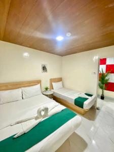 a bedroom with two beds and a green rug at RedDoorz at Urban Hotel in Zamboanga