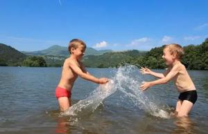 two young boys playing in the water in a lake at ZEcamping 4 étoiles familial - parc aqua et soirées animées in Murol