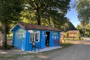 a blue shed with chairs in a park at ZEcamping 3 étoiles animaux acceptés bar épicerie et restaurant in Auxonne