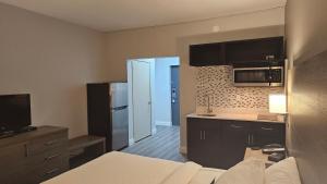 a room with a kitchen with a bed and a microwave at Motel 6 Sault Ste. Marie, ON in Sault Ste. Marie