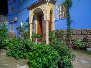 a blue building with an arch and plants at Dar jawhara in Chefchaouen