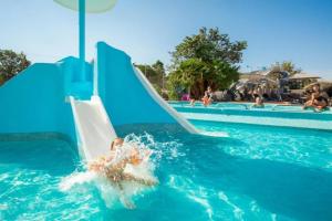 a person on a slide in the water at a pool at ZEcamping 4 familial piscine chauffée club enfant animations au calme in Canet-en-Roussillon +7 photos